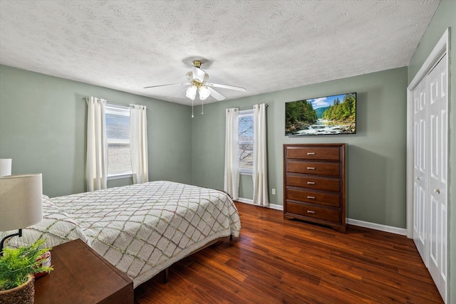 bedroom featuring a closet, baseboards, wood finished floors, and multiple windows