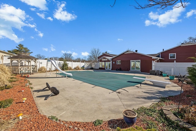 view of pool with a diving board, a patio, a water slide, and fence