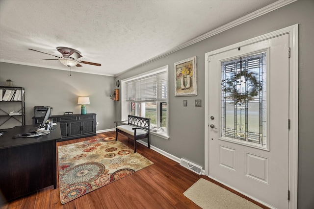 foyer with a textured ceiling, wood finished floors, visible vents, baseboards, and ornamental molding