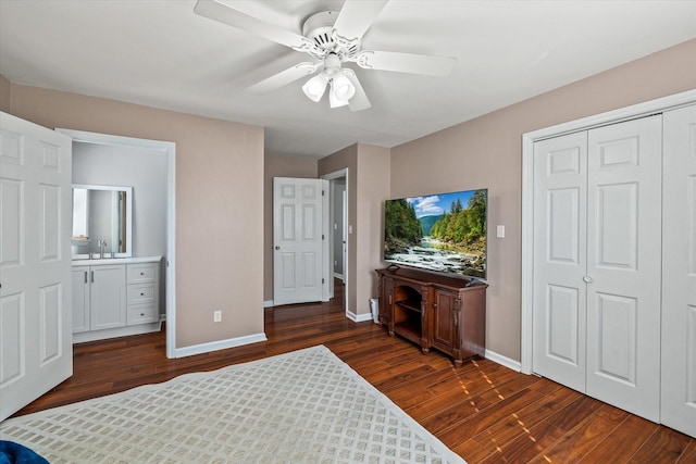 bedroom featuring baseboards, a ceiling fan, dark wood-style flooring, a sink, and a closet