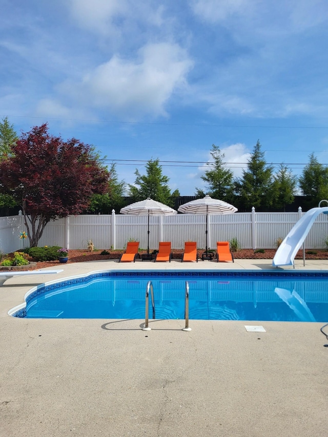 view of pool with a water slide, a fenced backyard, a diving board, a fenced in pool, and a patio area