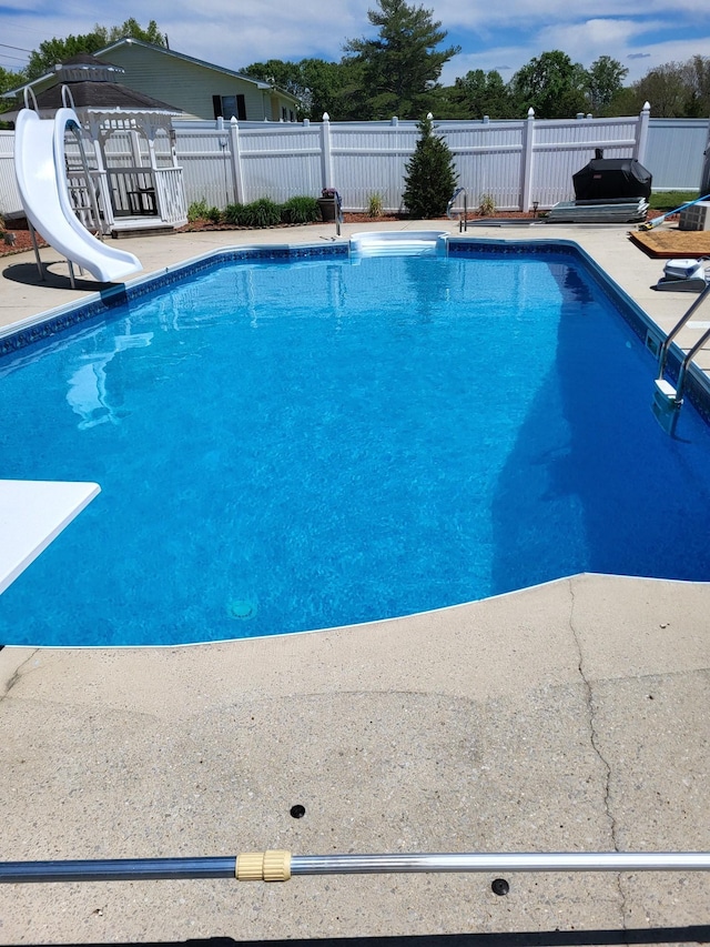 view of pool with a fenced in pool, a water slide, and fence