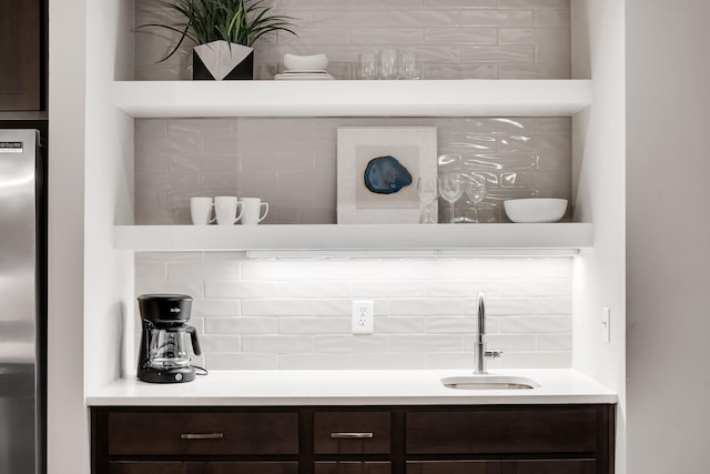 bar featuring tasteful backsplash, freestanding refrigerator, and a sink