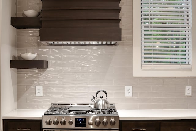 kitchen featuring stainless steel gas range, open shelves, dark brown cabinets, and light countertops