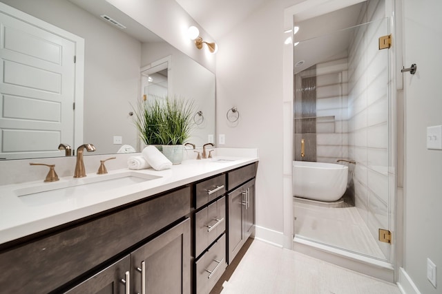 bathroom featuring visible vents, a sink, a freestanding bath, and double vanity