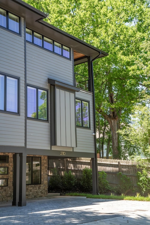 exterior space with stone siding, fence, and board and batten siding