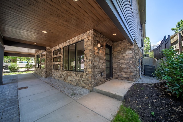 view of side of property with stone siding, a porch, and central AC