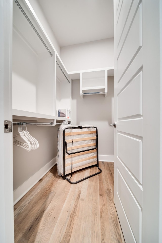 walk in closet featuring built in desk and light wood finished floors