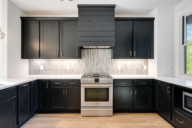 kitchen featuring light wood-type flooring, tasteful backsplash, appliances with stainless steel finishes, and light countertops