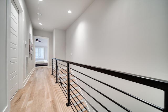 hallway with light wood finished floors, attic access, baseboards, an upstairs landing, and recessed lighting