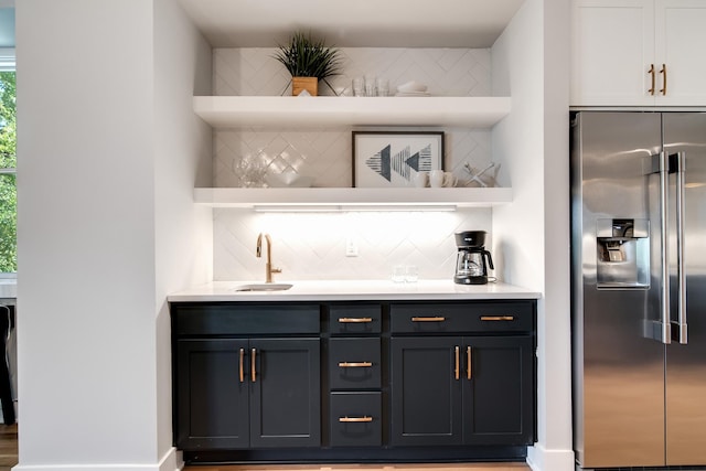 bar with high end fridge, indoor wet bar, a sink, and decorative backsplash