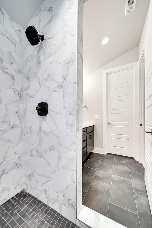 full bathroom featuring vaulted ceiling, visible vents, a tile shower, and vanity