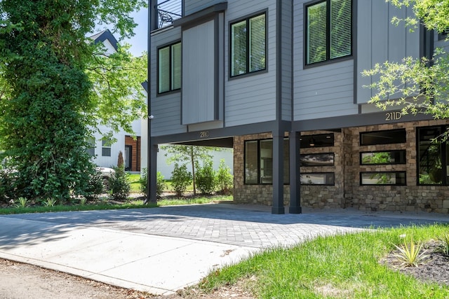 exterior space featuring stone siding and decorative driveway