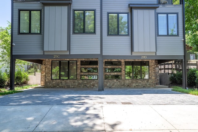 view of front of home featuring stone siding, board and batten siding, and driveway