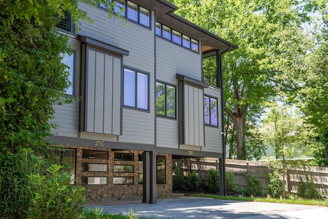 view of home's exterior with stone siding, fence, and board and batten siding