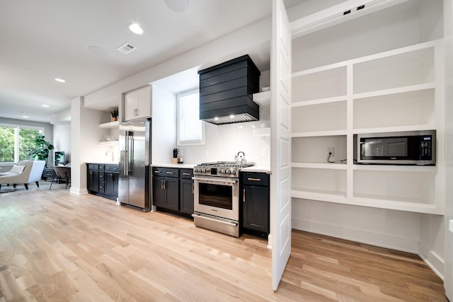 kitchen with custom exhaust hood, open shelves, a wealth of natural light, light wood-style flooring, and appliances with stainless steel finishes