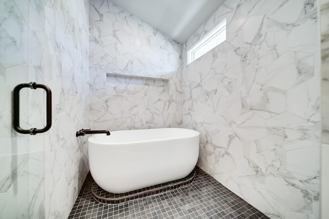 bathroom with a stall shower, a freestanding bath, tile walls, and tile patterned floors