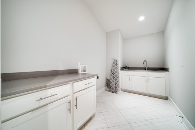 laundry area featuring hookup for a washing machine, cabinet space, a sink, and baseboards