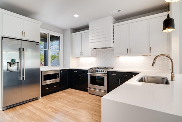 kitchen featuring white cabinetry, visible vents, a sink, and built in appliances