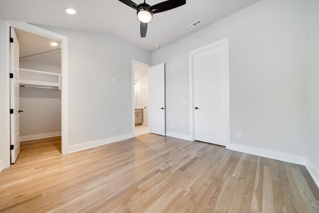 unfurnished bedroom with baseboards, a spacious closet, visible vents, and light wood-style floors