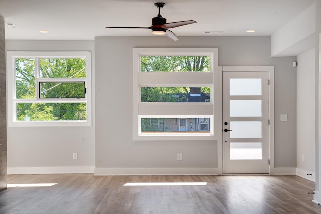 doorway to outside featuring a ceiling fan, visible vents, baseboards, and wood finished floors