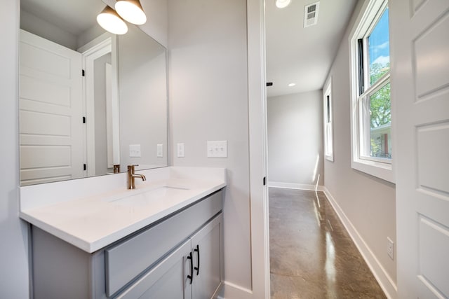 bathroom with finished concrete flooring, vanity, visible vents, and baseboards