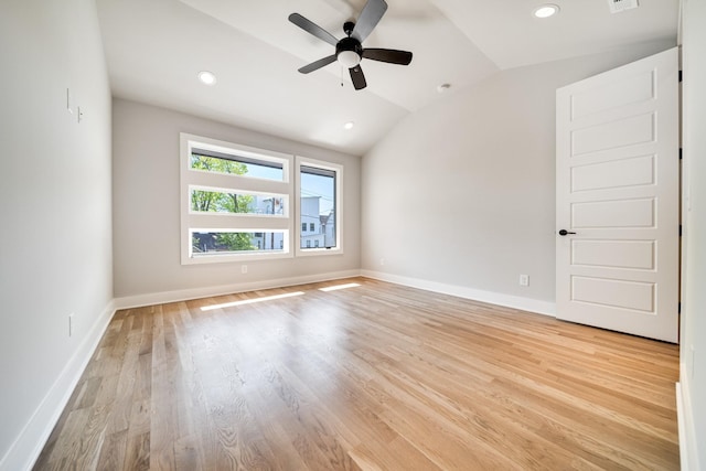 empty room featuring lofted ceiling, light wood-style flooring, baseboards, and recessed lighting