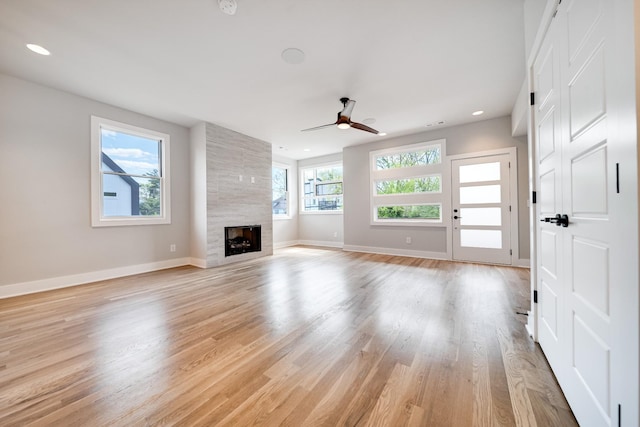 unfurnished living room featuring light wood finished floors, a fireplace, baseboards, and recessed lighting