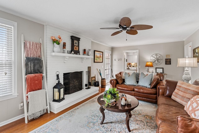living room with ornamental molding, a brick fireplace, wood finished floors, and a wealth of natural light