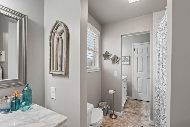 bathroom with a shower with shower curtain, baseboards, vanity, and toilet