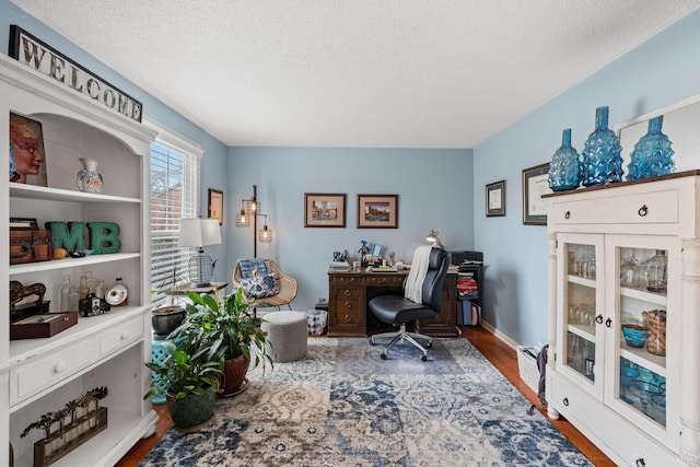 office space featuring a textured ceiling, wood finished floors, and baseboards