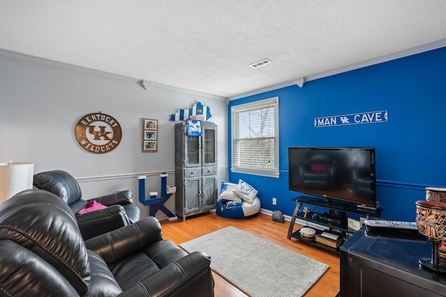living area featuring visible vents, a textured ceiling, baseboards, and wood finished floors