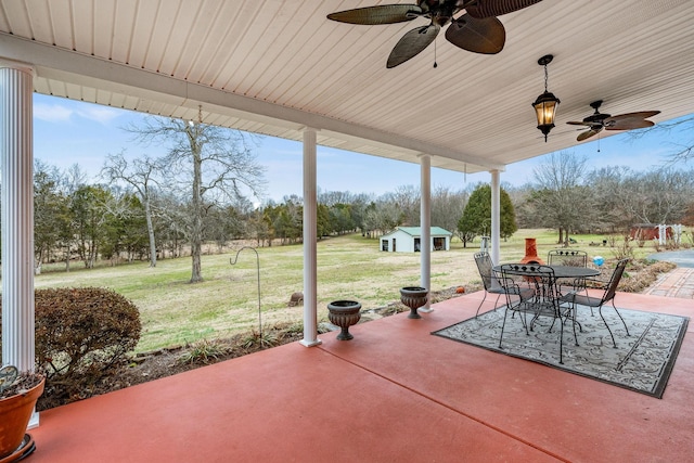 view of patio with a ceiling fan, outdoor dining area, and an outdoor structure