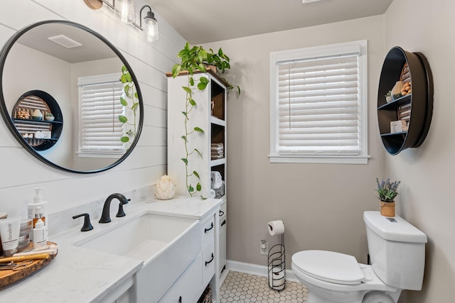 half bathroom with baseboards, visible vents, toilet, tile patterned flooring, and vanity