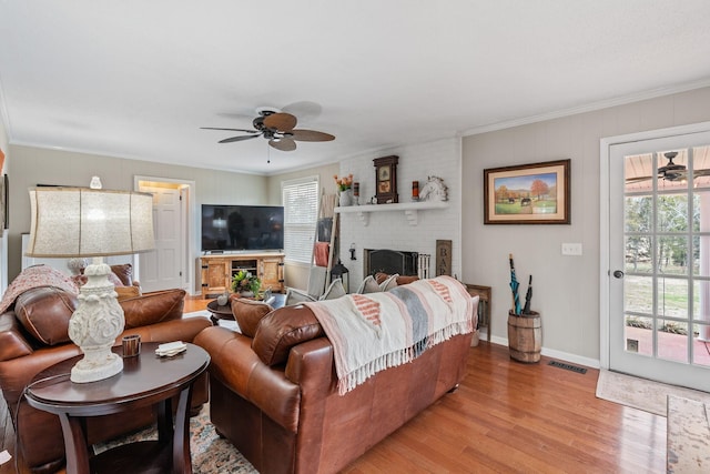 living room featuring a wealth of natural light, light wood-type flooring, visible vents, and a brick fireplace