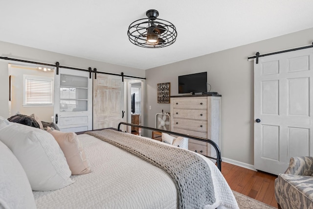 bedroom featuring wood finished floors, baseboards, and a barn door