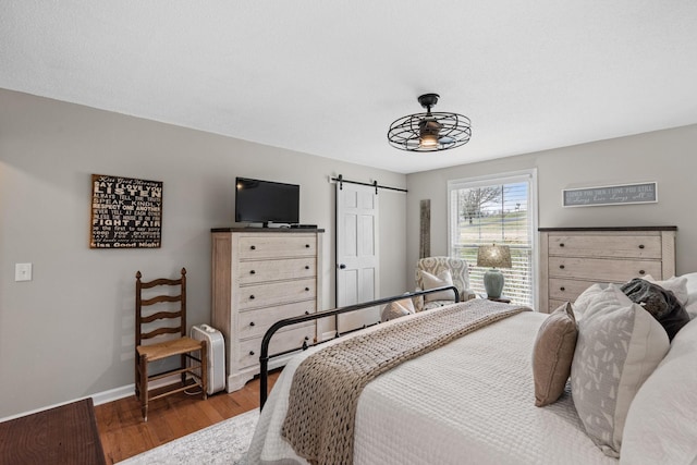 bedroom featuring a barn door, wood finished floors, and baseboards