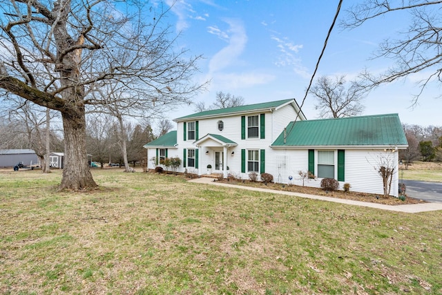 colonial-style house featuring metal roof and a front lawn