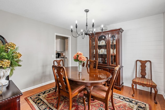 dining area featuring an inviting chandelier, baseboards, and wood finished floors