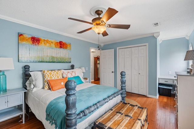 bedroom with visible vents, a ceiling fan, wood-type flooring, crown molding, and a closet