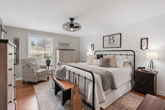 bedroom featuring a textured ceiling, wood finished floors, and baseboards