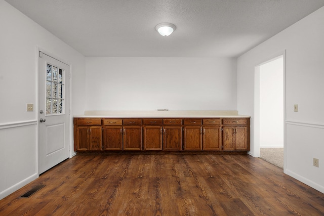 unfurnished room featuring baseboards, visible vents, and dark wood finished floors