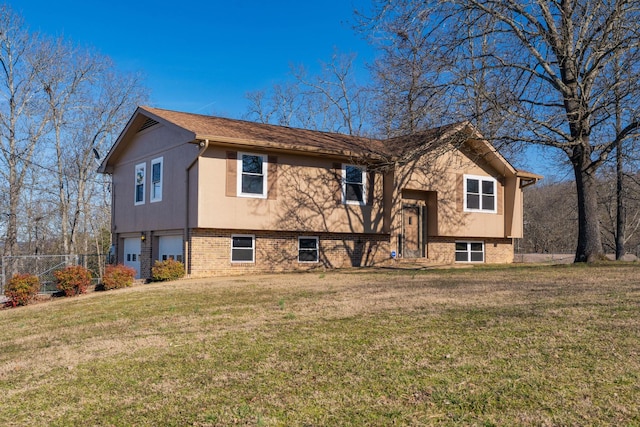 bi-level home featuring a garage, a front yard, brick siding, and fence