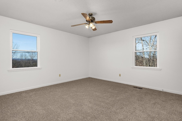 carpeted empty room with baseboards, visible vents, and ceiling fan