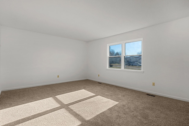 carpeted empty room with visible vents and baseboards