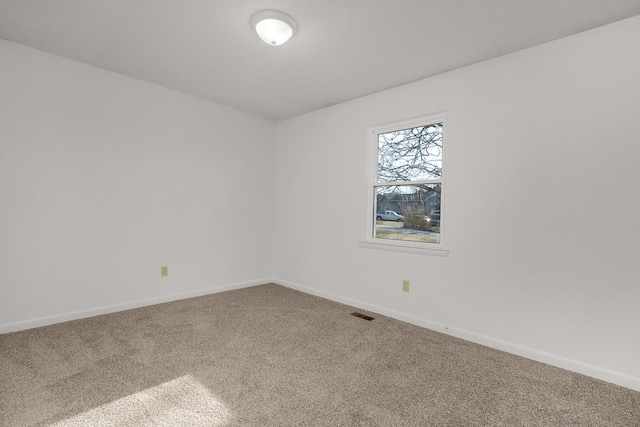 unfurnished room with carpet, visible vents, and baseboards