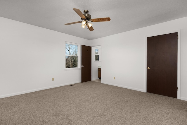 spare room with visible vents, carpet flooring, a ceiling fan, and baseboards