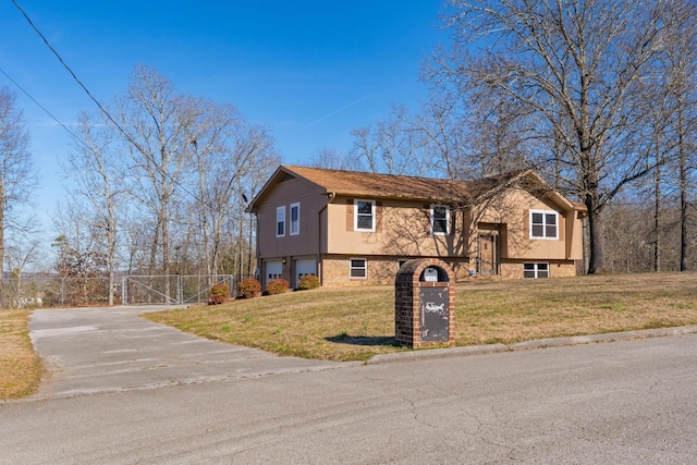 bi-level home featuring a front yard, a gate, fence, a garage, and driveway