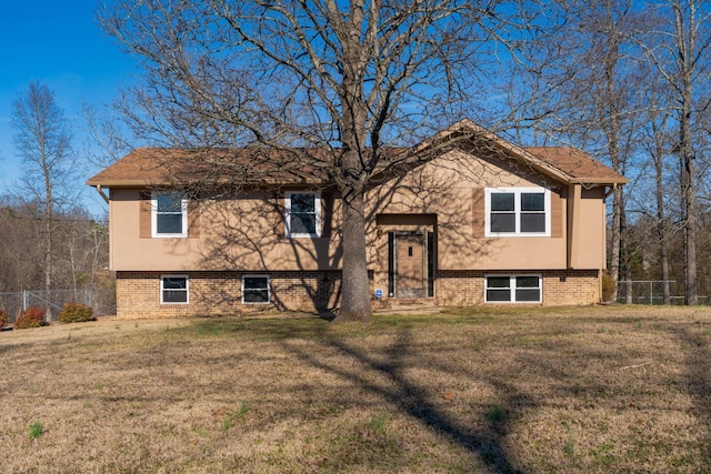 bi-level home featuring a front yard, brick siding, and fence