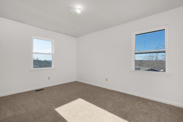 spare room featuring carpet floors, visible vents, and baseboards